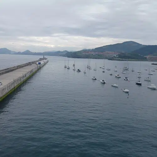 barcos en una bahía junto a un dique de hormigón por preparador lengua