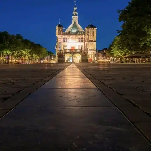 Iglesia iluminada en mitad de una plaza al anochecer